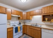 Thumbnail 7 of 16 - a kitchen with white appliances and wooden cabinets. Fargo, ND Crescent Park Apartments