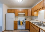 Thumbnail 8 of 16 - a kitchen with white appliances and wooden cabinets and a white refrigerator. Fargo, ND Crescent Park Apartments