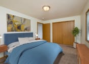 Thumbnail 3 of 11 - Fargo, ND Danbury Apartments. a bedroom with white walls and a blue bedspread