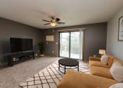 Thumbnail 1 of 11 - Fargo, ND Danbury Apartments. a living room with a ceiling fan and a sliding glass door to a balcony