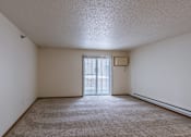 Thumbnail 24 of 28 - an empty living room with a sliding glass door to a balcony. Fargo, ND Eagle Run Apartments