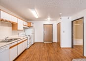 Thumbnail 27 of 28 - a kitchen with white appliances and wood flooring and a door to the bathroom. Fargo, ND Eagle Run Apartments