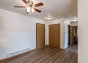 Thumbnail 23 of 28 - an empty living room with a ceiling fan and a closet. Fargo, ND Eagle Run Apartments