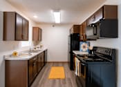 Thumbnail 21 of 28 - a kitchen with black appliances and brown cabinets and a black stove. Fargo, ND Eagle Run Apartments
