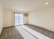 Thumbnail 19 of 28 - the living room of an apartment with carpet and a sliding glass door. Fargo, ND Eagle Run Apartments