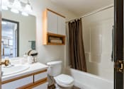 Thumbnail 18 of 28 - a bathroom with a shower toilet and sink and a mirror. Fargo, ND Eagle Run Apartments