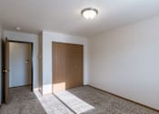 Thumbnail 17 of 28 - a bedroom with white walls and a door to a closet. Fargo, ND Eagle Run Apartments