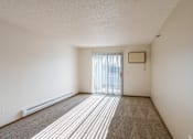 Thumbnail 13 of 28 - an empty living room with a sliding glass door to a balcony. Fargo, ND Eagle Run Apartments