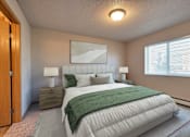 Thumbnail 3 of 12 - a bedroom with a white bed and a green blanket. Fargo, ND East Bridge Apartments