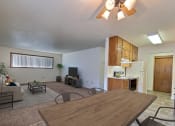 Thumbnail 2 of 12 - a living room with a wooden table and chairs and a kitchen with a refrigerator and stove. Fargo, ND Emerald Apartments