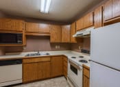 Thumbnail 14 of 19 - an empty kitchen with white appliances and wooden cabinets. Fargo, ND Galleria Apartments