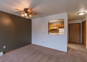 Thumbnail 15 of 19 - an empty living room with a ceiling fan and a kitchen. Fargo, ND Galleria Apartments