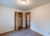 Thumbnail 8 of 19 - a bedroom with a carpeted floor and a hallway with two doors and a closet. Fargo, ND Galleria 3 Apartments
