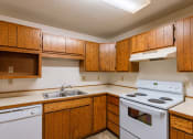Thumbnail 6 of 19 - an empty kitchen with white appliances and wooden cabinets. Fargo, ND Galleria 3 Apartments
