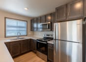 Thumbnail 6 of 24 - An updated kitchen with stainless steel appliances and dark wood cabinets. Fargo, ND Granger Court Apartments.