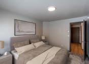 Thumbnail 4 of 24 - a bedroom with a bed and a door to the hallway. Fargo, ND Granger Court Apartments