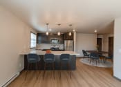 Thumbnail 2 of 24 - a kitchen with an island with four chairs and a dining room with a table. Fargo, ND Granger Court Apartments