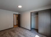Thumbnail 10 of 24 - An empty room with a closet and a door to a wardrobe. Fargo, ND Granger Court Apartments.