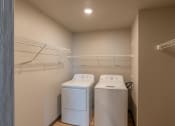 Thumbnail 11 of 24 - A laundry room with two washes and a dryer in it and a closet. Fargo, ND Granger Court Apartments.