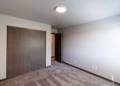 Thumbnail 18 of 24 - Granger Court Apartments in Fargo, ND | a bedroom with a door to a closet and a carpeted floor