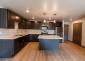 Thumbnail 15 of 24 - A kitchen with dark wood cabinets and a white counter top. Fargo, ND Granger Court Apartments.
