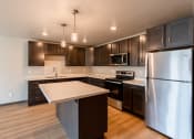Thumbnail 14 of 24 - A kitchen with stainless steel appliances and dark wood cabinets. Fargo, ND Granger Court Apartments.