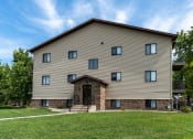 Thumbnail 24 of 24 - An apartment building with a grassy yard in front of it. Fargo, ND Granger Court Apartments.