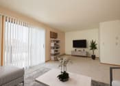 Thumbnail 2 of 9 - Fargo, ND Hunters Run Apartments. A living room with a tv, coffee table, and bookshelf with a large sliding glass door that brightens up the room with natural light.