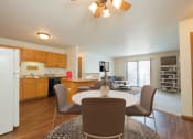 Thumbnail 3 of 9 - Fargo, ND Hunters Run Apartments. A dining area with a table and four chairs and a kitchen in the background.