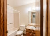 Thumbnail 12 of 13 - A bathroom with a toilet sink and tub and a mirror. Fargo, ND Huntington Apartments.
