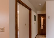 Thumbnail 11 of 13 - The view of the hallway from the living room with the door open to the bathroom and bedroom with a closet door with a mirror. Fargo, ND Huntington Apartments.
