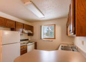 Thumbnail 8 of 13 - A kitchen with white appliances and wooden cabinets. Fargo, ND Huntington Apartments.