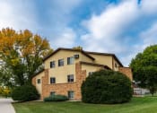 Thumbnail 13 of 13 - The view of an apartment building with green grass and trees. Fargo, ND Huntington Apartments.