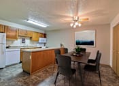 Thumbnail 3 of 20 - a dining area with a table and chairs and a kitchen in the background. Fargo, ND Kennedy Apartments