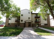 Thumbnail 14 of 14 - An apartment building with a sidewalk and trees. Fargo, ND Kentwood Apartments