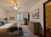 Thumbnail 6 of 18 - Fargo, ND Kingswood Apartments.  A bedroom with a bed and a dresser a large walk in closet is in the back corner of the room along with a window to brighten the room with natural light