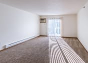 Thumbnail 6 of 49 - a spacious living room with carpet and a door to a balcony. Fargo, ND Lake Crest Apartments