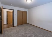 Thumbnail 15 of 49 - a bedroom with carpet and a door to a closet. Fargo, ND Lake Crest Apartments