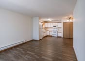 Thumbnail 11 of 49 - an empty living room and kitchen with wood flooring and white cabinets. Fargo, ND Lake Crest Apartments