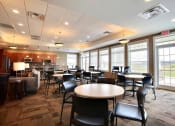 Thumbnail 44 of 49 - Fargo, ND Lake Crest Apartments. A large room with tables and chairs and a kitchen in the background