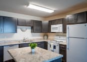 Thumbnail 28 of 49 - Fargo, ND Lake Crest Apartments. A kitchen with a white stove top oven next to a refrigerator