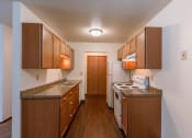 Thumbnail 8 of 30 - A kitchen with wooden cabinets and a white stove and refrigerator. Fargo, ND Long Island Apartments.