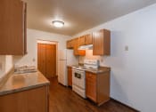 Thumbnail 9 of 30 - A kitchen with wooden cabinets and white appliances and a sink. Fargo, ND Long Island Apartments.