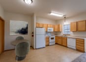 Thumbnail 3 of 13 - a kitchen with white appliances and wooden cabinets and a table. Moorhead, MN Townhomes at Mallard Creek