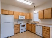 Thumbnail 7 of 13 - a kitchen with white appliances and wooden cabinets and a window above the sink. Moorhead, MN Mallard Creek Apartments
