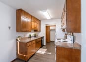 Thumbnail 9 of 20 - a kitchen with wooden cabinets and a white stove and refrigerator. Fargo, ND Martha Alice Apartments