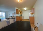 Thumbnail 5 of 17 - a dining room table with a view of the kitchen and living room of an apartment. Fargo, ND Maybrook Apartments