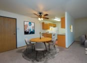 Thumbnail 2 of 17 - a living room with a dining room table and a kitchen. Fargo, ND Maybrook Apartments