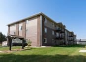 Thumbnail 16 of 17 - a large apartment building with a sign in front of it. Fargo, ND Maybrook Apartments