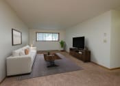 Thumbnail 4 of 26 - Fargo, ND Monticello. A living room with a white couch and a wooden coffee table in front of a flat-screen tv. A window fills the room with natural light.